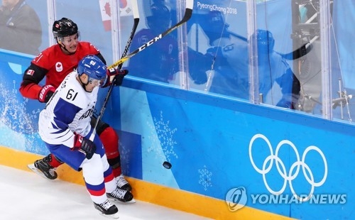 In this file photo from Feb. 18, 2018, South Korean defenseman Lee Don-ku (R) battles Canadian forward Mason Raymond for the loose puck during their Group A match in the men's hockey tournament at the 2018 PyeongChang Winter Olympics at Gangneung Hockey Centre in Gangneung, 230 kilometers east of Seoul. (Yonhap)