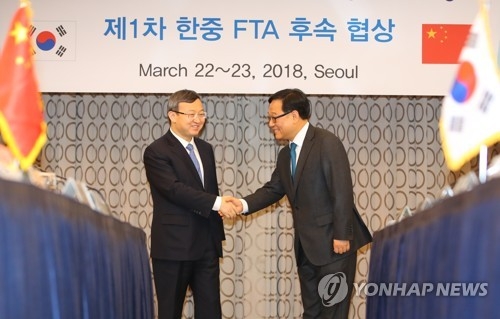 Kim Young-sam (R), a deputy minister of trade and investment at South Korea's Ministry of Trade, Industry and Energy, shakes hands with Wang Shouwen (L), vice Chinese commerce minister, during the first round of follow-up negotiations for the countries' bilateral trade agreement in Seoul on March 22, 2018. (Yonhap)