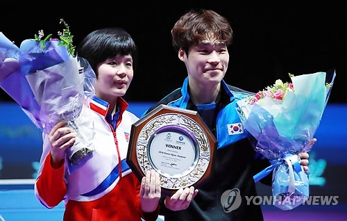 Cha Hyo-sim of North Korea (L) and Jang Woo-jin of South Korea pose with the champions' trophy after winning the gold medal in the mixed doubles at the International Table Tennis Federation (ITTF) World Tour Platinum Korea Open at Chungmu Sports Arena in Daejeon, 160 kilometers south of Seoul, on July 21, 2018. (Yonhap)