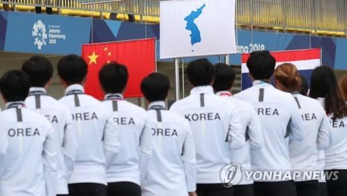 In this file photo from Aug. 26, 2018, members of the unified Korean dragon boat racing team stand on the podium after winning gold in the women's 500-meter competition at the 18th Asian Games at the Jakabaring Rowing & Canoeing Regatta Course in Palembang, Indonesia. (Yonhap)