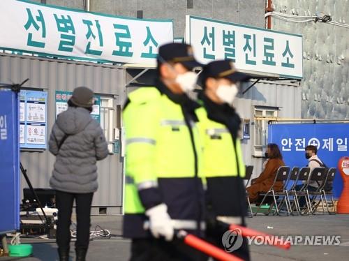 Police officers wearing masks stand guard at a medical center in Daegu, 300 kilometers southeast of Seoul, on Feb. 20, 2020, as people suspected of having been infected with the new coronavirus arrive to receive tests. (Yonhap)