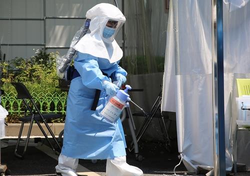A heavily geared medical worker disinfects a COVID-19 screening station in Daejeon, central South Korea, on June 10, 2020. (Yonhap)