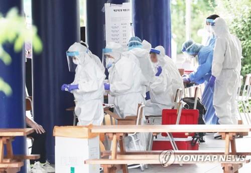 Health workers clad in protective gear prepare to work at a coronavirus screening clinic at a high school in Yongin, south of Seoul, on Aug. 13, 2020. (Yonhap)