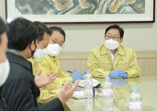 Justice Minister Park Beom-kye (R) listens to a business executive during his visit to an industrial complex, northeast of Seoul, on Feb. 19, 2021, where massive coronavirus infections of foreign workers were reported, in this photo provided by his office. (PHOTO NOT FOR SALE) (Yonhap)