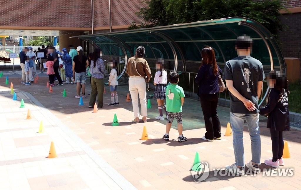 Des élèves et parents font la queue devant un centre de dépistage provisoire installé dans une école élémentaire à Incheon le vendredi 29 mai 2020, pour subir un test de dépistage du nouveau coronavirus (Covid-19), alors que de nombreux cas confirmés ont été rapportés dans cette ville ces jours-ci.