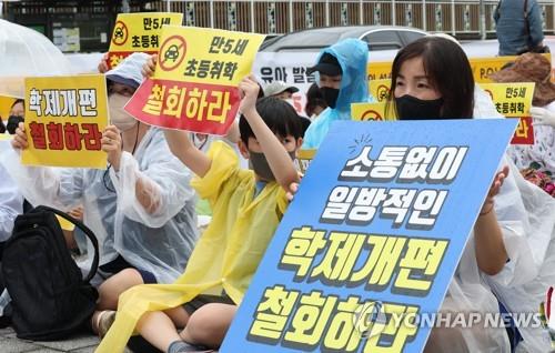 Des manifestants brandissent des pancartes lors d'un rassemblement devant le Mémorial de la guerre de Corée à Séoul le 2 août 2022, exigeant que le gouvernement abandonne sa proposition d'abaisser l'âge d'entrée à l'école.