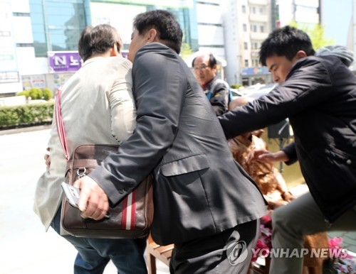警察に阻止される男性（左端）＝１９日、釜山（聯合ニュース）