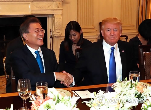 ６月２９日、米ワシントンで行われた夕食会で握手を交わす文大統領（左）とトランプ大統領＝（聯合ニュース）