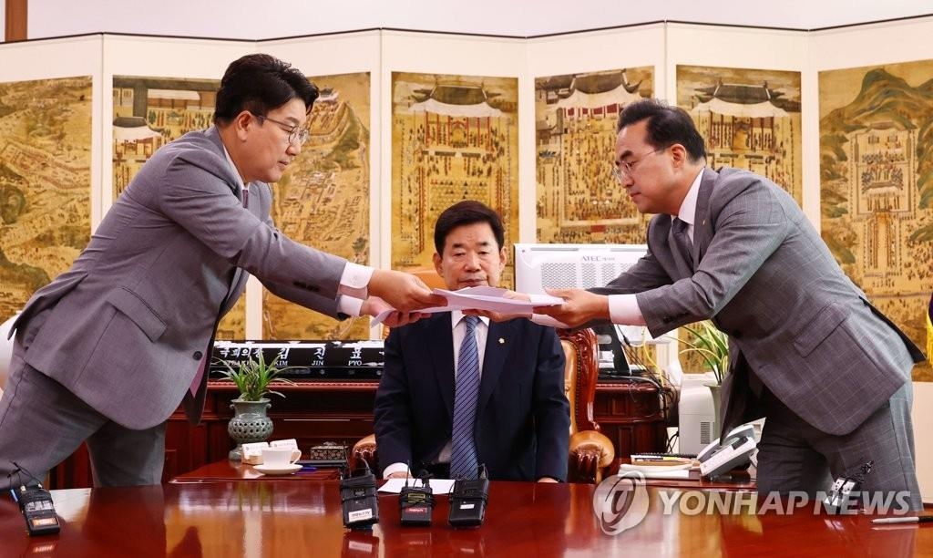 金振杓(キム・ジンピョ)国会議長の前で合意文を取り交わす国民の力の権性東(クォン・ソンドン)党代表職務代行兼院内代表(左)と共に民主党の朴洪根(パク・ホングン)院内代表(国会写真記者団)=22日、ソウル(聯合ニュース)