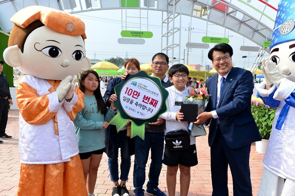 10만번째 입장객인 강대규(가운데)씨 가족이 이근규(오른쪽) 제천시장과 기념촬영을 하고 있다.