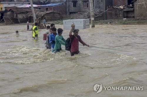 폭우로 불어난 물을 건너는 네팔 주민. [AP=연합뉴스]