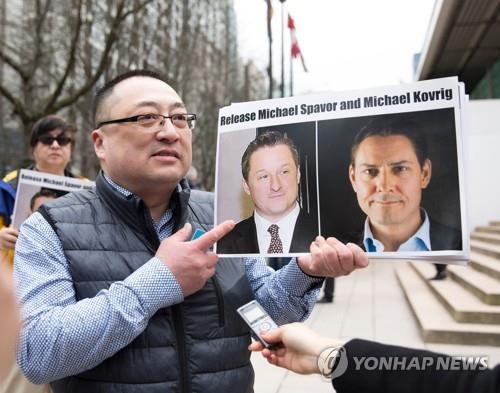 중국 구금 캐나다인 2명의 사진을 들고 석방을 요구하는 시위대 [AFP=연합뉴스]