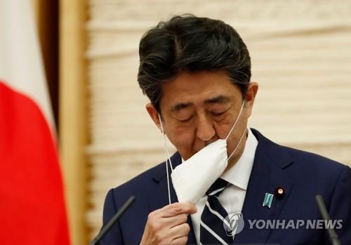 (도쿄 AFP=연합뉴스) 아베 신조(安倍晋三) 일본 총리가 25일 일본 총리관저에서 열린 기자회견에서 발언에 앞서 마스크를 벗고 있다. 2020.5.31