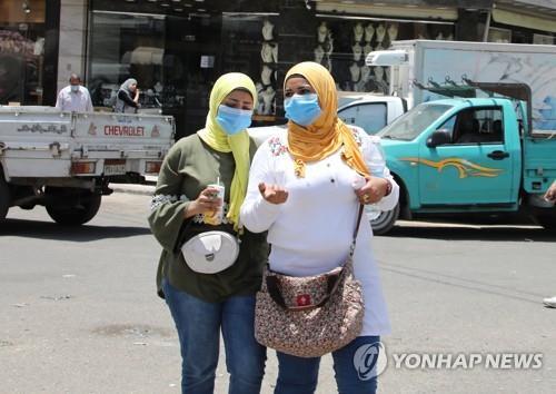 지난 6월 11일 이집트 수도 카이로의 한 거리에서 마스크를 쓰고 걷는 시민들.