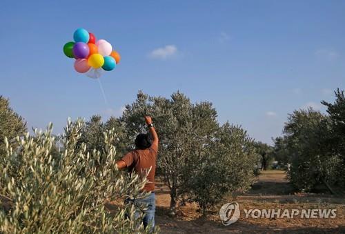 12일(현지시간) 가자지구에서 이스라엘 남부로 폭발물과 인화성 물질을 단 풍선을 날리려고 준비하는 팔레스타인 남성 [AFP=연합뉴스 자료사진]