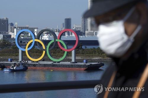 (도쿄 AP=연합뉴스) 지난달 1일 일본 도쿄도(東京都)에서 마스크를 쓴 남성이 이동하는 가운데 오다이바 해변 공원에 도쿄올림픽을 상징하는 조형물이 보인다. 신종 코로나바이러스 감염증(코로나19)이 급격하게 확산하면서 도쿄 올림픽·패럴림픽 개최가 어렵다는 관측이 대두하고 있다.