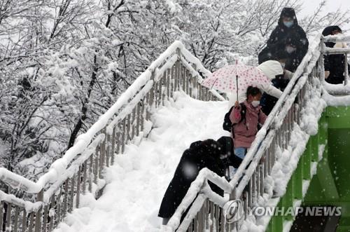 (강릉=연합뉴스) 이해용 기자 = 강원 동해안과 산지에 폭설이 내린 2일 오전 강릉 시내 초등학생들이 육교를 건너 등교하고 있다. 2021.3.2