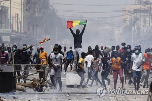 5일 세네갈 수도 다카르에서 한 시위 참가자가 국기를 두손 높이 들고 있다.