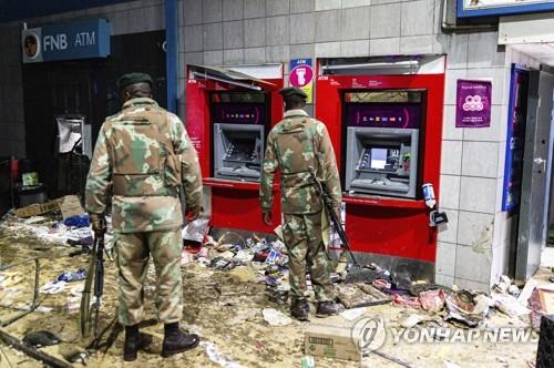 지난 12일 소웨토 약탈 현장에서 은행 자동화기기를 지키는 군인들 