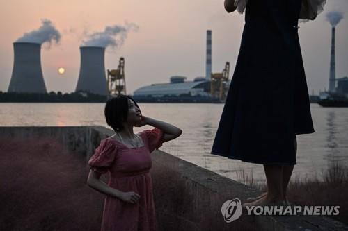 28일 상하이의 석탄 발전소를 배경으로 한 여성이 포즈를 취하고 있다. [AFP=연합뉴스]