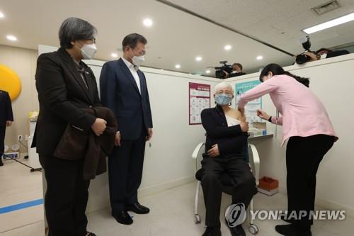El presidente, Moon Jae-in (2º por la izda.), observa a un doctor que recibe la vacuna contra el COVID-19 de AstraZeneca, el 26 de febrero de 2021, en un centro de salud pública, en Seúl, el día en que el país comenzó la vacunación a nivel nacional, a las 9:00 a.m.