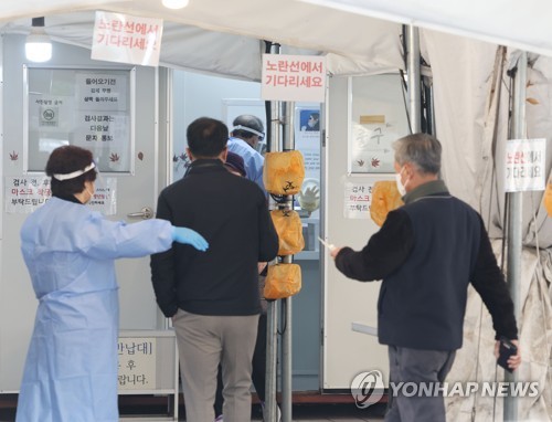 Una trabajadora médica guía a los visitantes, el 21 de noviembre de 222, en una clínica provisional de exámenes, en el distrito de Nowon, en el norte de Seúl.