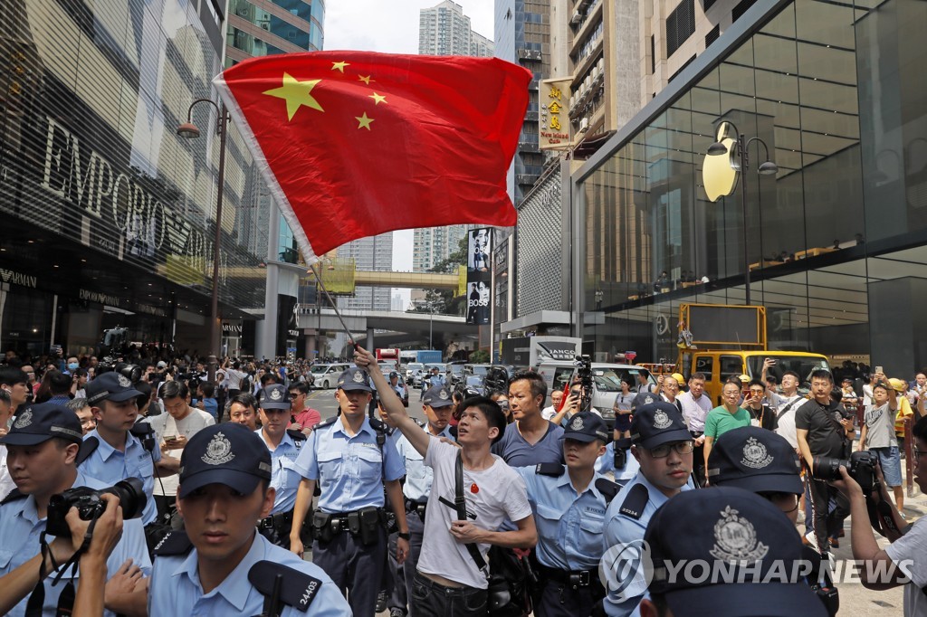 18일 홍콩 쇼핑몰에서 경찰의 보호를 받으며 중국 국기를 흔드는 중국 지지자