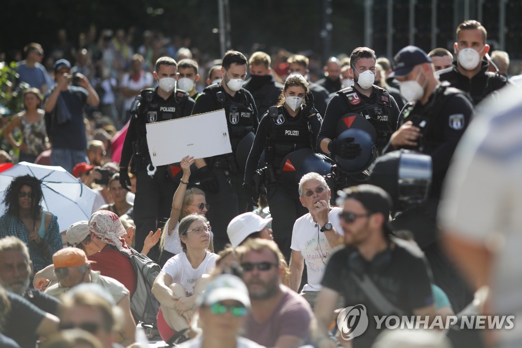 브란덴부르크문 앞에서 열린 코로나19 공공생활 통제 반대 집회에서 참석자들 사이를 지나가는 경찰 [AP=연합뉴스]