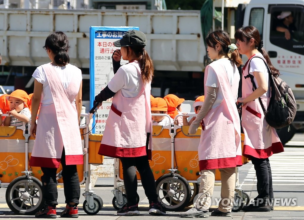 일본 도쿄도의 거리에서 보육사들이 보육원에서 돌보는 어린 아이들을 손수레에 태우고 나온 모습 [연합뉴스 자료사진]