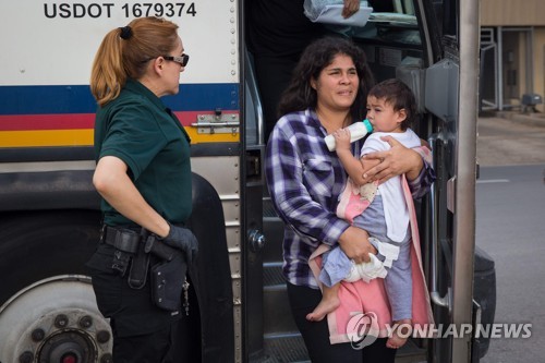 아이를 안고 버스에서 내리는 불법 이민자. 미 정부는 밀입국자 무관용 정책에 따라 미국 국경을 넘다가 발각된 부모를 구금하고, 자녀는 다른 시설에 격리 수용하고 있다. [AFP=연합뉴스]