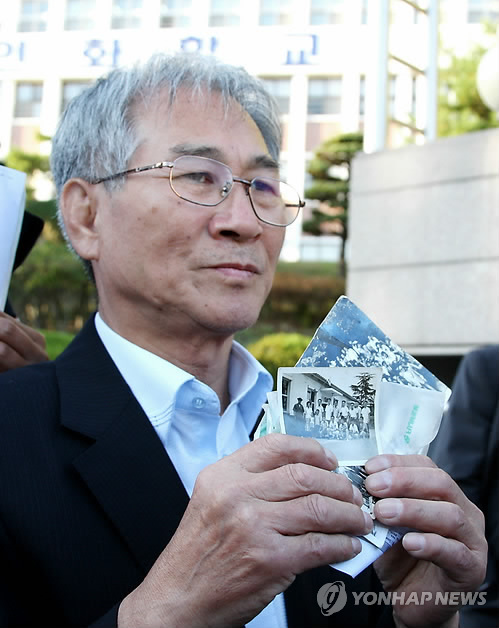 인화학교 전직 교사였던 김영일(71)씨가 지난 17일 오후 광주 광산구 삼거동 인화학교 앞에서 50여년 전 학생을 숨지게 한 후 암매장한 당시 인화학교 교감의 사진을 보여주고 있다 (자료사진)