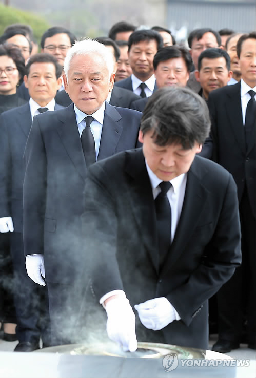 20일 오후 광주 북구 운정동 국립 5·18민주묘지를 찾은 김한길 새정치민주연합 공동창당준비위원장이 분향하는 안철수 공동창당위원장의 모습을 바라보고 있다.