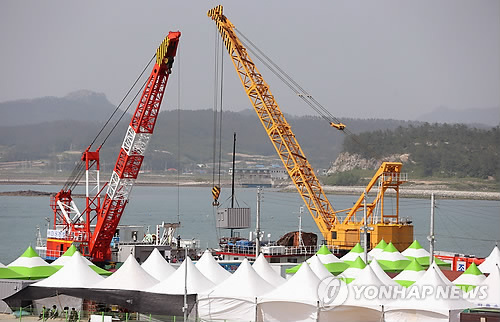 선체 절단 작업에 투입될 새 바지(화물운반선)는 예정보다 뒤늦게 사고해역에 도착했다. 사진은 28일 오후 전남 진도 팽목항에서 세월호 부분 절단 작업에 새롭게 참여할 팔팔 128호 바지(화물운반선)가 그동안 사고해역에서 수색 작업에 참가했던 DS-1 바지와 임무 교대를 위해 컨테이너를 옮겨 싣는 작업을 하는 모습.