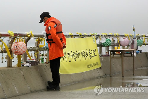 지난 3일 오후 팽목항 등대 앞에서 한 소방관이 바다를 바라보고 있다. 팽목항 곳곳에는 모든 실종자가 가족의 품으로 돌아갈 수 있는 플래 카드가 걸려 있다.