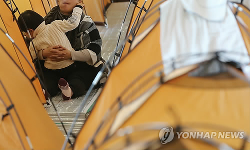 지난달 11일 경기도 의정부시 의정부3동 경의초등학교에 차려진 아파트 화재 이재민 대피소에서 아기가 어머니 품에 안겨 있다. (연합뉴스 자료사진)