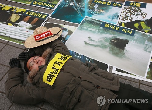 2015년 12월 24일 오전 서울 서대문구 경찰청 앞에서 '민주노총 공안탄압 현황 발표 및 무더기 사법처리 규탄 기자회견'에서 한 참가자가 같은 해 11월 14일 서울 도심 집회에서 백남기씨가 경찰의 물대포에 맞고 쓰러진 모습을 재연하고 있다. <<연합뉴스 자료사진>>