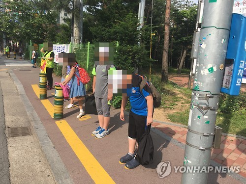 노란 발자국 위에서 녹색 신호 기다리는 어린이