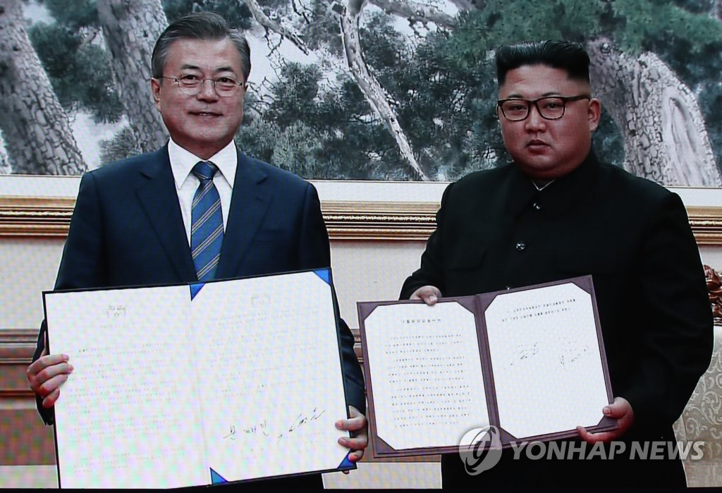 The captured image of a live broadcast from Pyongyang shows South Korean President Moon Jae-in (L) and North Korean leader Kim Jong-un holding their joint declaration signed at the end of their bilateral summit held in the North Korean capital on Sept. 19, 2018. (Yonhap)