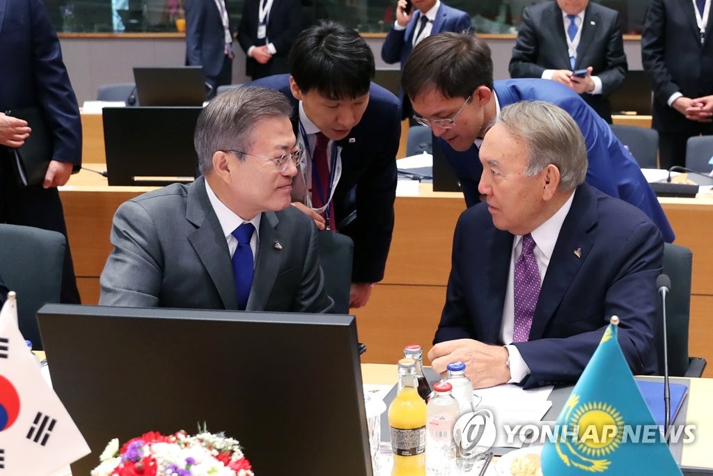 South Korean President Moon Jae-in (L) speaks with his Kazakh counterpart, Nursultan Nazarbayev, while attending the first session of the biennial Asia-Europe Meeting summit in Brussels on Oct. 19, 2018. (Yonhap)