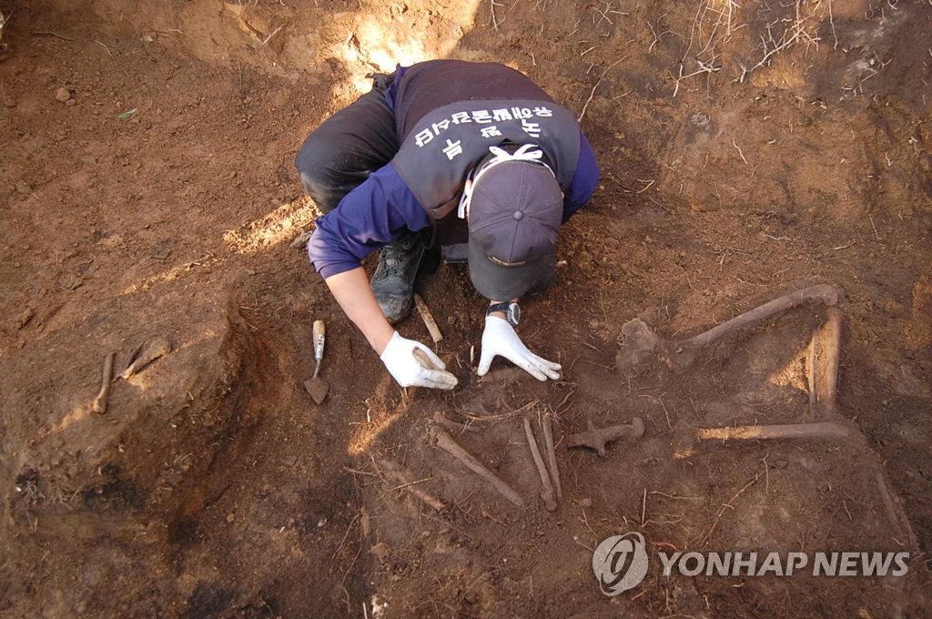 In the photo, provided by South Korea's defense ministry, a member of the Agency for KIA Recovery and Identification is seen excavating the remains of a soldier killed in action during the 1950-53 Korean War in the town of Inje, Gangwon Province. (PHOTO NOT FOR SALE) (Yonhap)