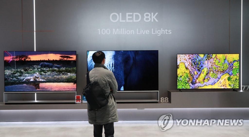 This photo taken on Jan. 7, 2020, shows a reporter looking at LG Electronics Inc.'s OLED 8K TVs at the company's exhibition booth at the Consumer Electronics Show in Las Vegas, Nevada. (Yonhap)