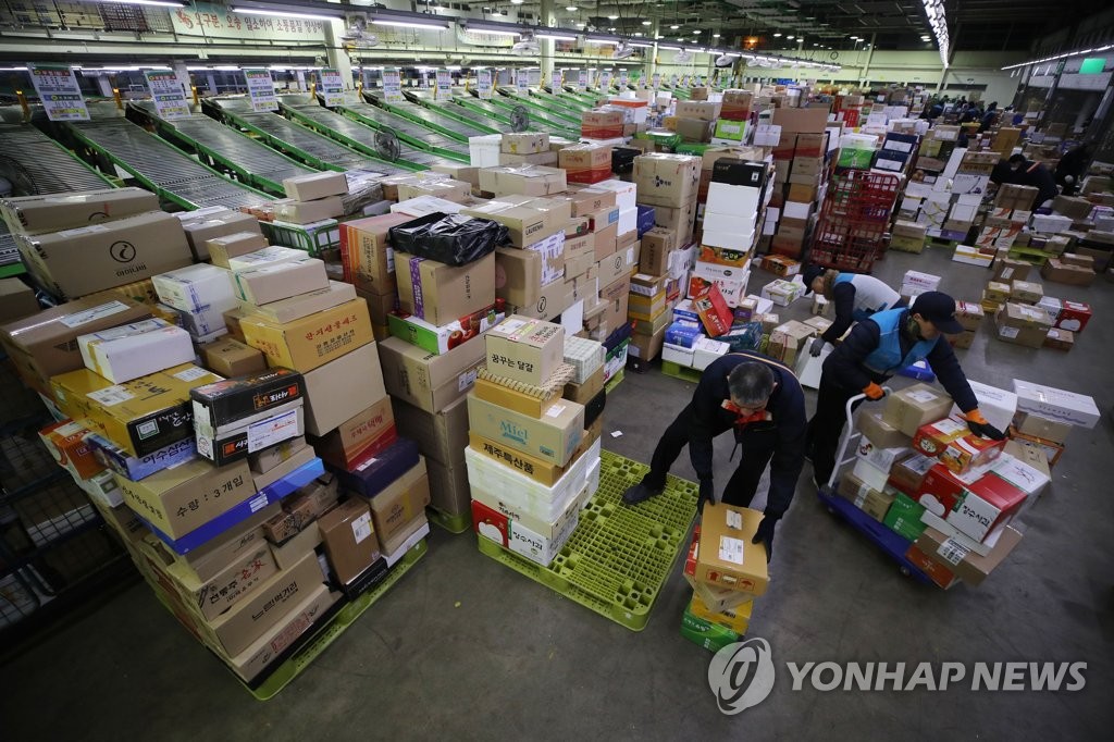 Workers at a logistics center affiliated with Korea Post in eastern Seoul sort deliveries on Jan. 14, 2020, ahead of the Lunar New Year holiday. (Yonhap)