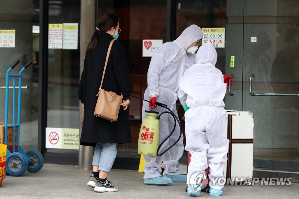 A Chinese student at Gwangju University in the southwestern city of Gwangju is helped by school officials before entering the dormitory on Feb. 28, 2020. (Yonhap)