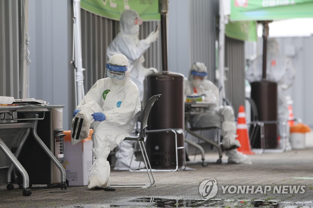 Medical staff members get ready for work at a drive-thru testing center located in southern Seoul on April 20, 2020. (Yonhap)
