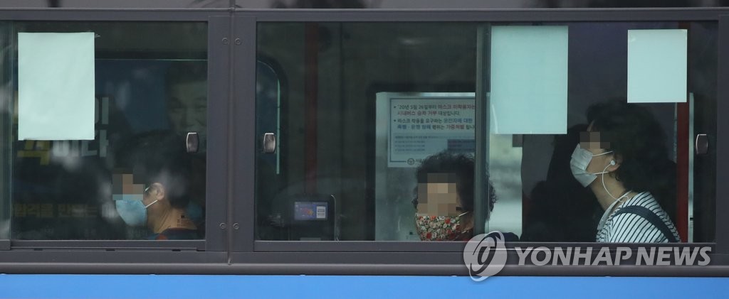 Passengers on a bus passing through central Seoul wear face masks on Aug. 25, 2020. (Yonhap)