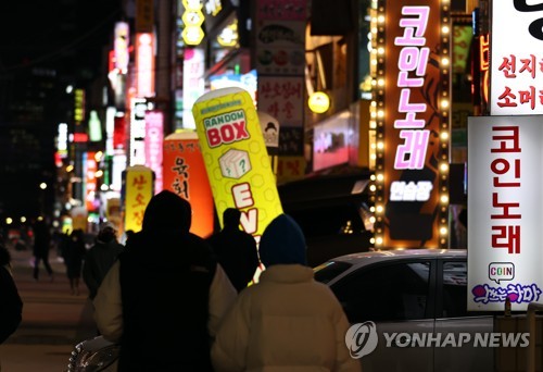 Signs for coin-operated karaoke rooms are illuminated in Seoul on Jan. 18, 2021, as health authorities eased restrictions on cafes, gyms and other indoor facilities the same day amid signs of a letup in new coronavirus cases. (Yonhap)