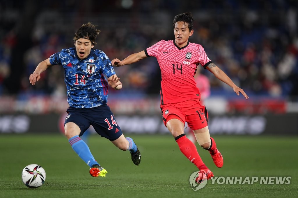 Hong Chul of South Korea (R) battles Junya Ito of Japan for the ball during their friendly football match at Nissan Stadium in Yokohama, Japan, on March 25, 2021, in this photo provided by the Korea Football Association. (PHOTO NOT FOR SALE) (Yonhap)