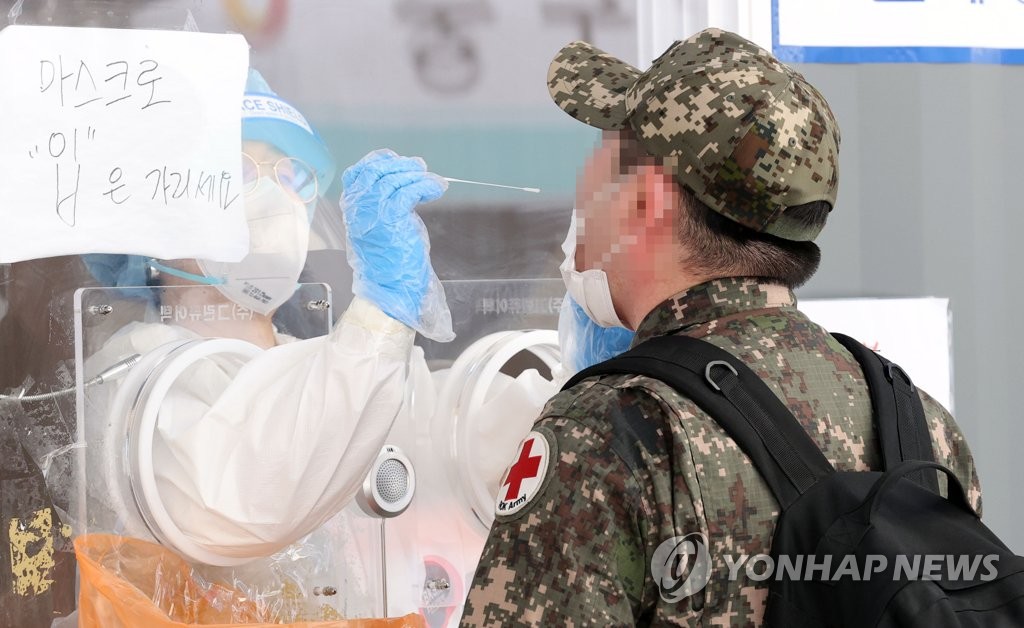 A military personnel member takes a COVID-19 test at a testing booth near Seoul Station in Seoul on May 24, 2021. (Yonhap) 