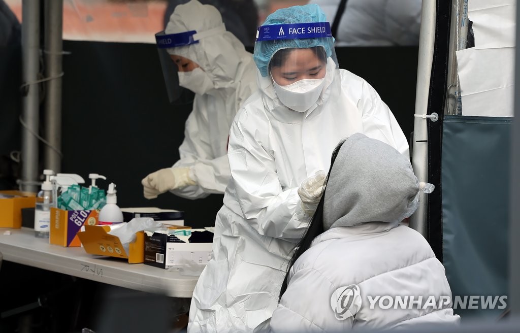 Medical workers carry out rapid antigen tests at a COVID-19 testing station in Seoul on Feb. 13, 2022. (Yonhap)