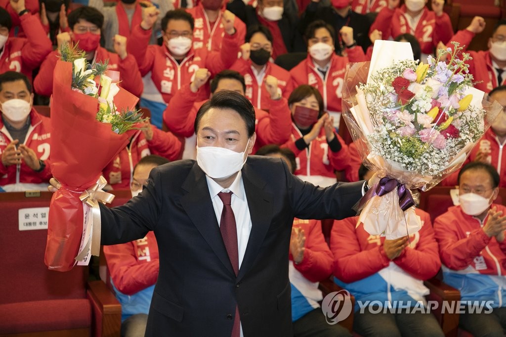 President-elect Yoon Suk-yeol poses for photos after receiving flowers in his party's election situation room at the National Assembly in Seoul on March 10, 2022. (Pool photo) (Yonhap)
